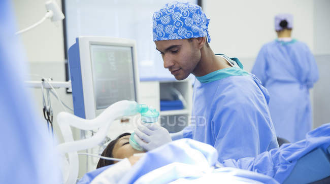 Anesthesiologist holding oxygen mask over patients face in operating room — Stock Photo