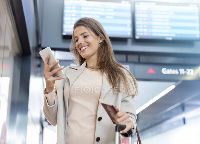 Бізнес-леді з паспортом за допомогою мобільного телефону в аеропорту — стокове фото