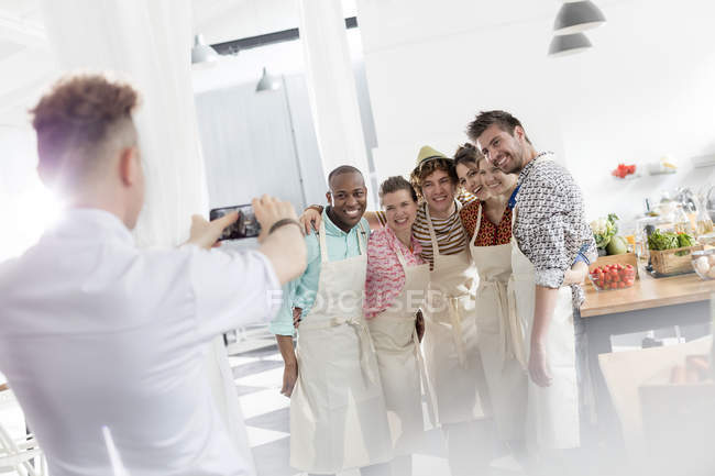 Chef teacher photographing students with camera phone in cooking class kitchen — Stock Photo