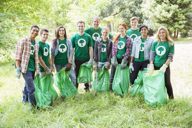Retrato de voluntarios ecologistas sonrientes recogiendo basura - foto de stock