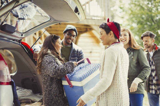 Friends unloading backpack at back of car — Stock Photo
