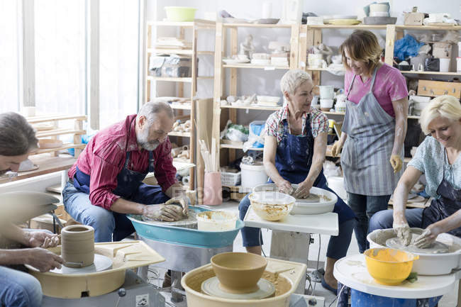 Mature students using pottery wheels in studio — Stock Photo