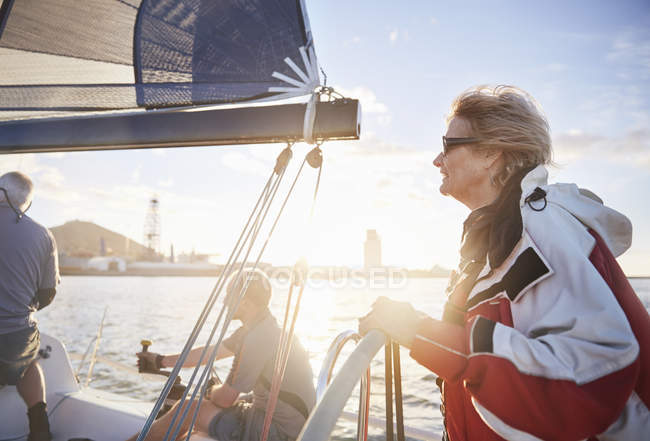 Woman sailing steering sailboat at helm on sunny ocean — Stock Photo