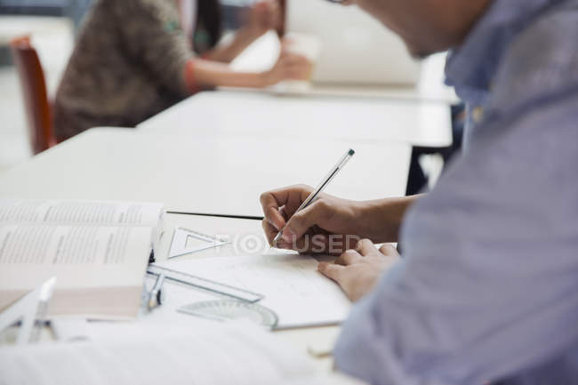 Cropped image of male college student doing geometry math homework in library — Stock Photo