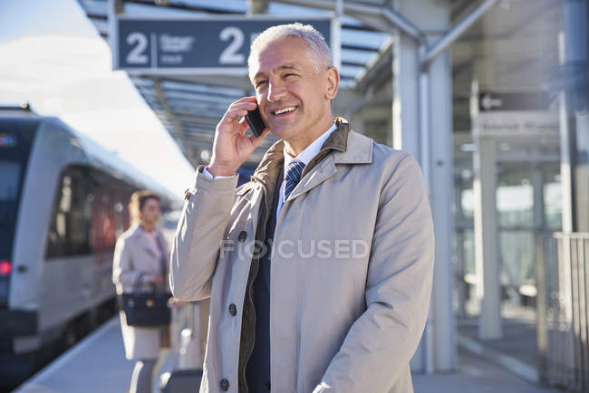 Hombre de negocios sonriente hablando por teléfono celular fuera del aeropuerto - foto de stock