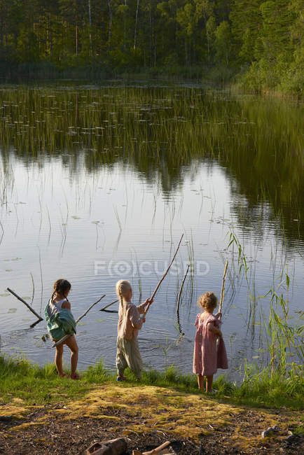 Girls fishing at sunny lakeside — Stock Photo