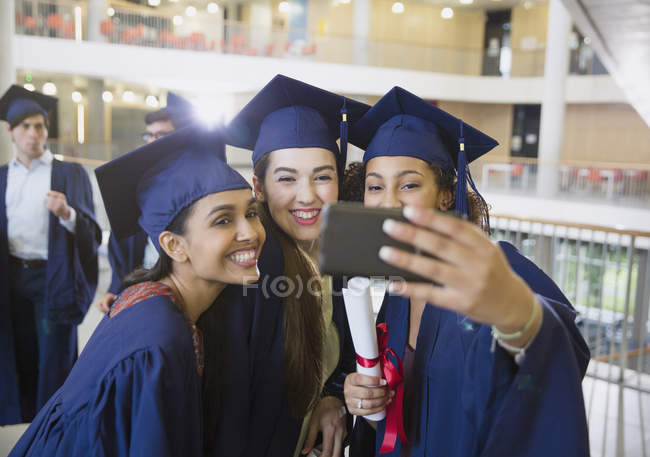 College-Absolventinnen in Mütze und Kleid machen Selfie — Stockfoto