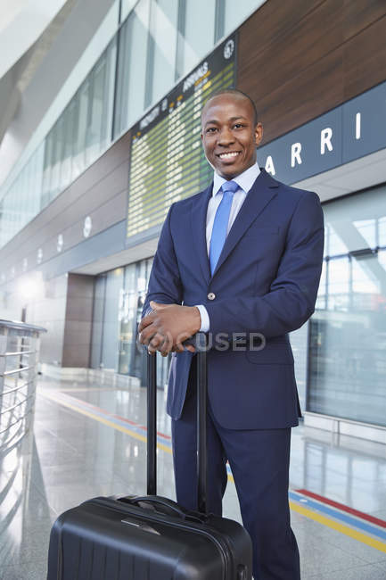 Ritratto uomo d'affari sicuro di sé con valigia nella hall dell'aeroporto — Foto stock