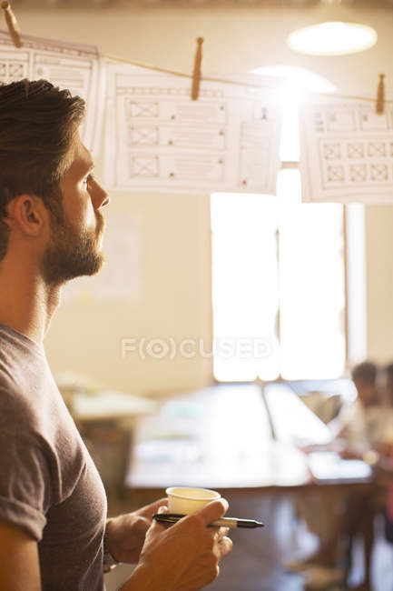 Pensive casual businessman reviewing hanging diagrams in office — Stock Photo