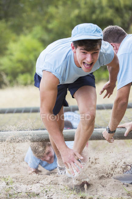 Homem determinado correndo no campo de inicialização curso de obstáculo — Fotografia de Stock