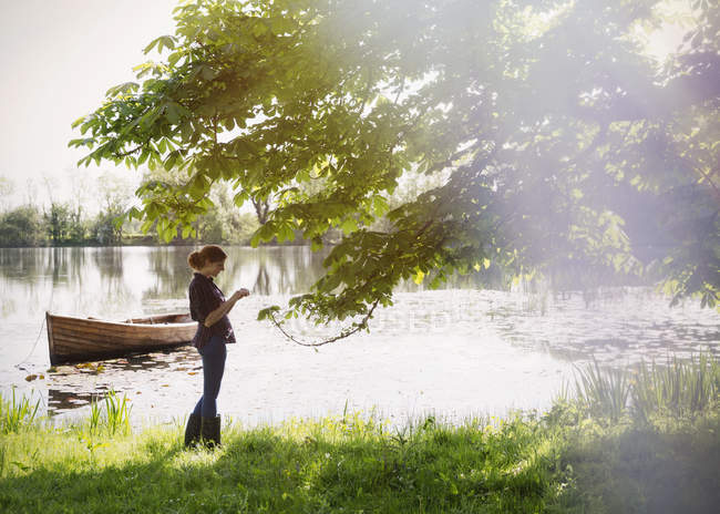 Femme debout au bord du lac idyllique ensoleillé — Photo de stock
