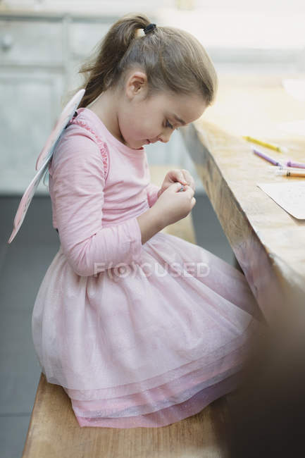 Menina em asas de fada colorir na mesa de jantar — Fotografia de Stock