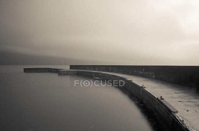 Monochrome image of old pier over water — Stock Photo