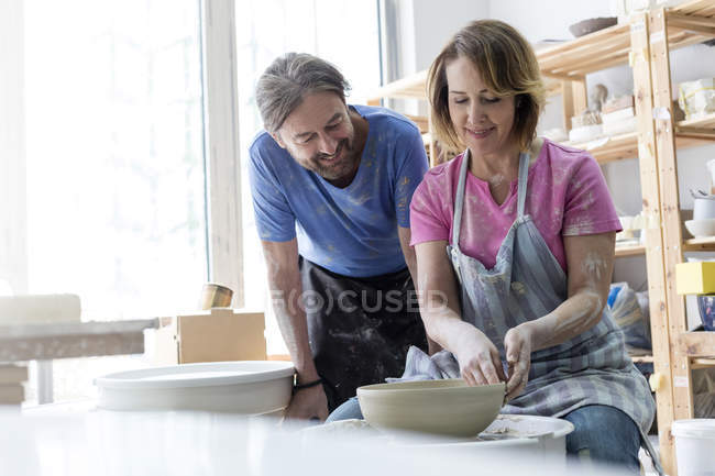 Mature couple using pottery wheel in studio — Stock Photo