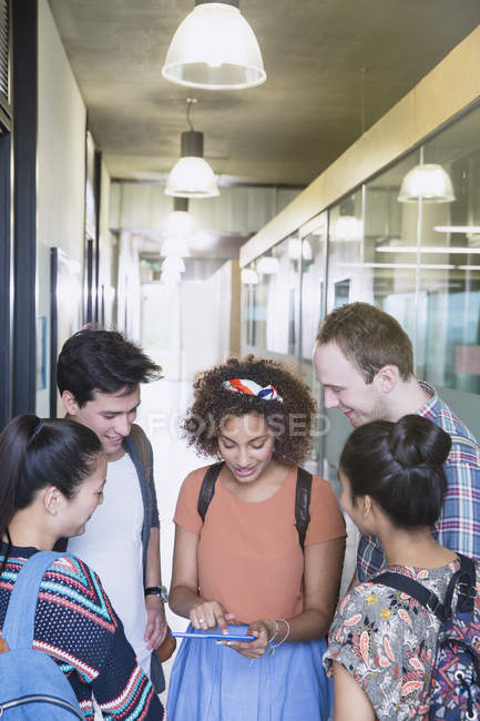 Estudiantes universitarios usando tableta digital en corredor - foto de stock