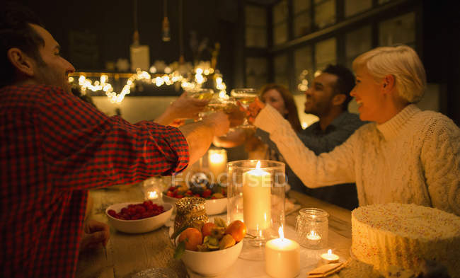 Friends toasting champagne glasses at candlelight Christmas dinner party — Stock Photo