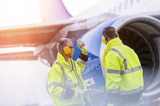 Airport ground crew workers talking near airplane — Stock Photo