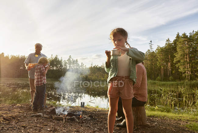Großeltern und Enkel kochen am Seeufer im Wald — Stockfoto