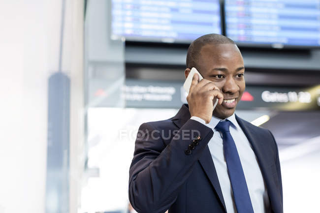 Businessman talking on cell phone in airport — Stock Photo
