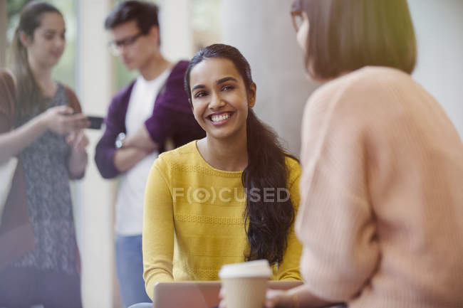 Lächelnde Studentinnen, die Kaffee trinken und reden — Stockfoto