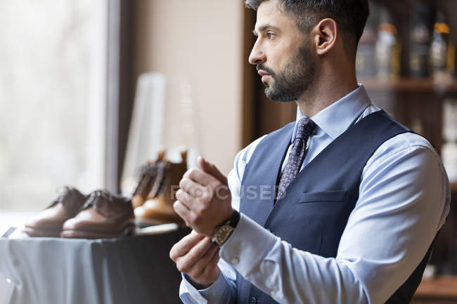Businessman looking through window in menswear shop — Stock Photo