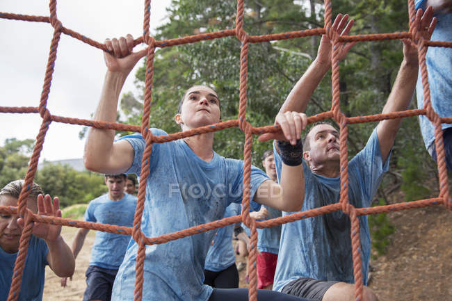 Determined woman climbing net at boot camp obstacle course — Stock Photo