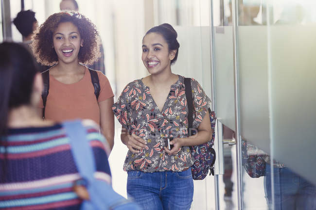Sorridente studentesse universitari che camminano in corridoio — Foto stock