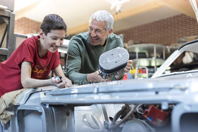 Отец и сын восстанавливают автомобильный двигатель — стоковое фото
