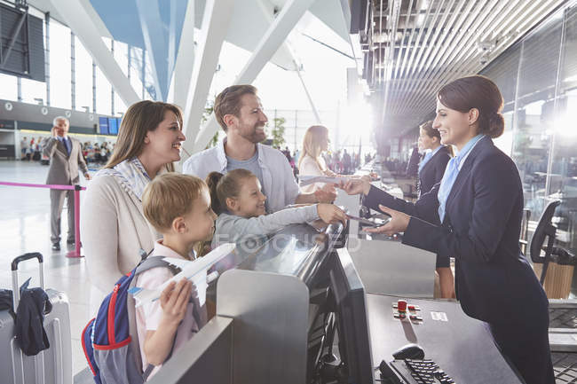 Rappresentante del servizio clienti che controlla i biglietti per la famiglia al banco del check-in in aeroporto — Foto stock