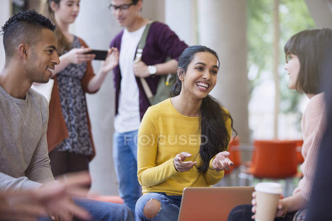 Улыбающиеся студенты колледжа разговаривают и пьют кофе в общежитии — стоковое фото