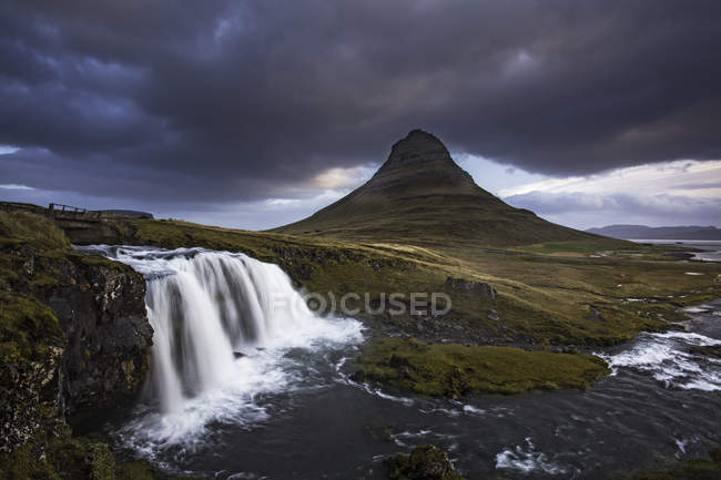 Wasserfall von felsigen Klippen und Hügeln im Hintergrund — Stockfoto