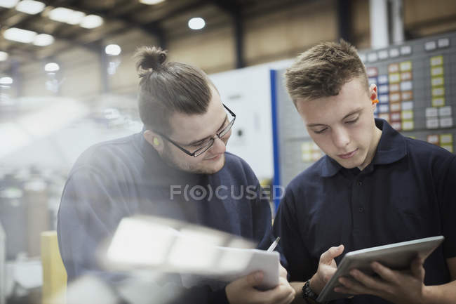 Trabajadores con papeleo y tableta digital en fábrica de acero - foto de stock