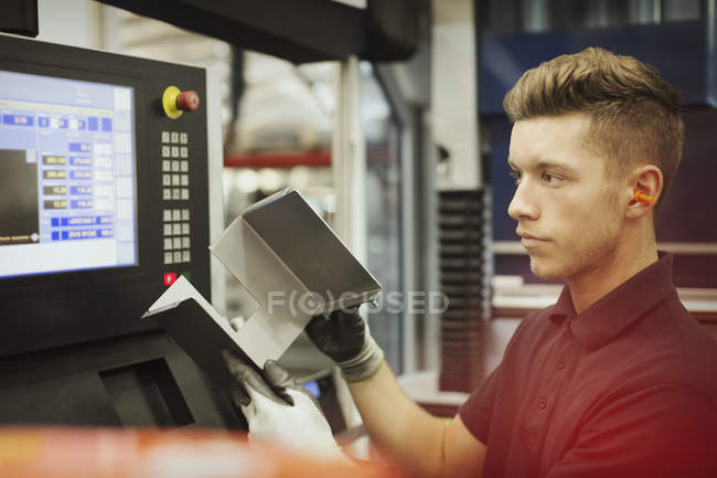Worker with part at control panel in steel factory — Stock Photo