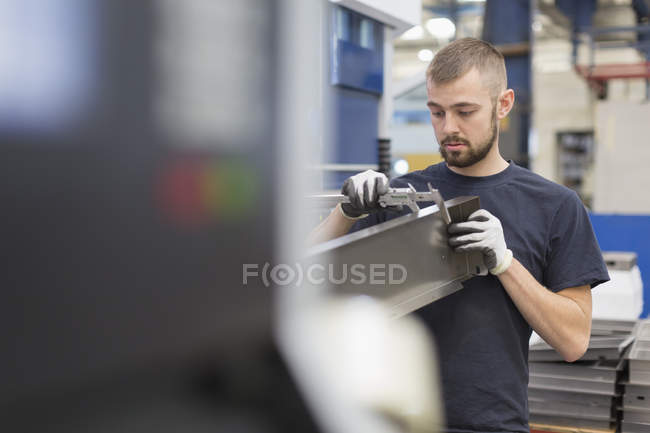 Worker measuring steel with calipers in steel factory — Stock Photo