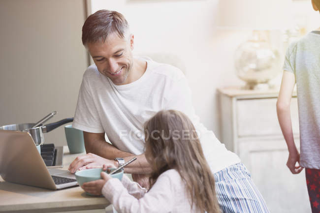 Padre e hija disfrutando del desayuno en el portátil - foto de stock