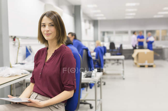 Portrait confident businesswoman with digital tablet in steel factory office — Stock Photo