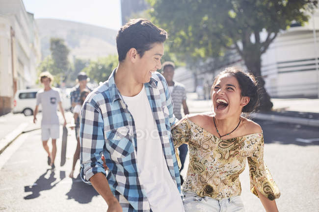 Смеющаяся подростковая пара на солнечной городской улице — стоковое фото