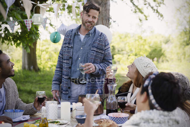 Мужчина тост за друзьями за садовым столом — стоковое фото