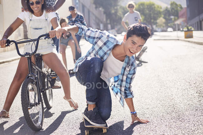 Portrait adolescent souriant skateboard avec des amis sur la rue urbaine ensoleillée — Photo de stock