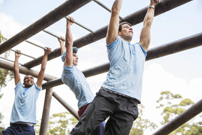 Hombres en barras de mono en el campo de entrenamiento - foto de stock