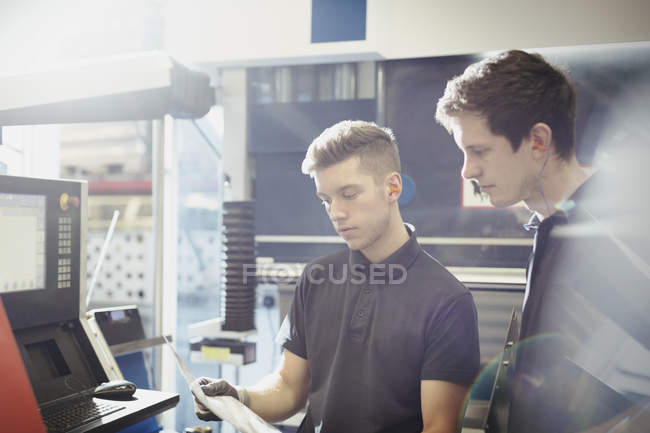 Lavoratori che esaminano le pratiche burocratiche presso il pannello di controllo delle macchine in acciaieria — Foto stock
