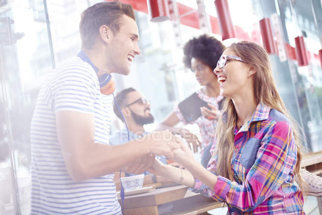 Пара сміється і тримає руки в кафе — стокове фото