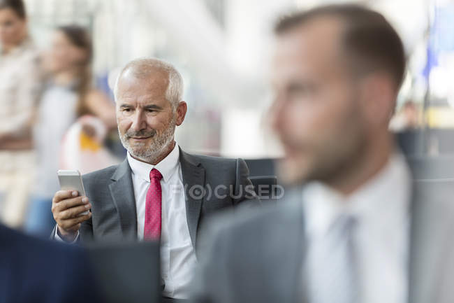 Homme d'affaires textos avec téléphone portable dans la zone de départ de l'aéroport — Photo de stock