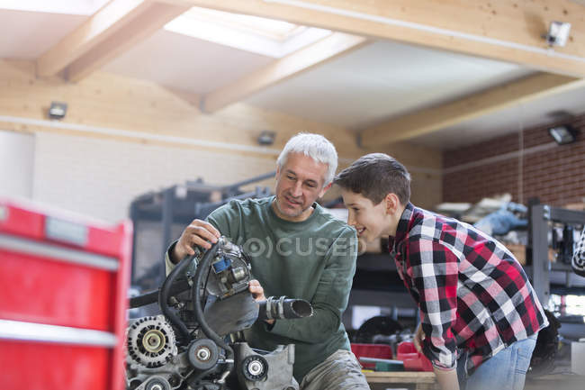 Pai e filho reconstruindo motor na oficina de reparação de automóveis — Fotografia de Stock