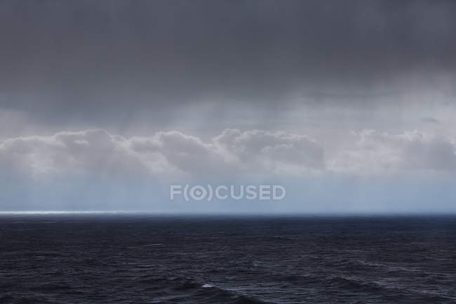 Nubes y lluvia sobre el paisaje marino - foto de stock