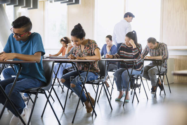 Professor watching college students taking test in classroom — Stock Photo