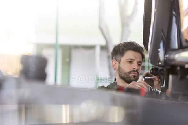 Focused mechanic repairing car in auto repair shop — Stock Photo