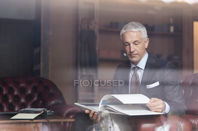 Businessman browsing book in menswear shop — Stock Photo