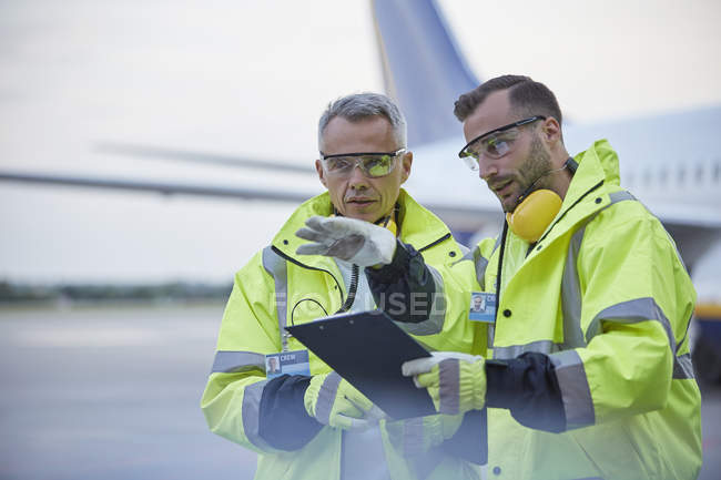 Air traffic control ground crew workers with clipboard talking on airport tarmac — Stock Photo