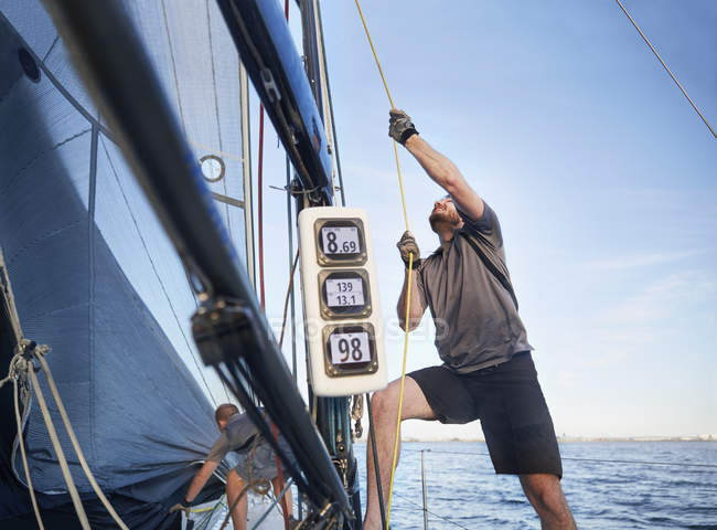 Чоловік регулює вітрильне обладнання на вітрильному човні — стокове фото